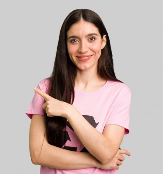 Smiling young woman in a pink shirt pointing to the side, promoting Sarkari Yojana initiatives.